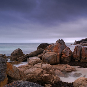 photograph of rocks and seascape w/ purple sky